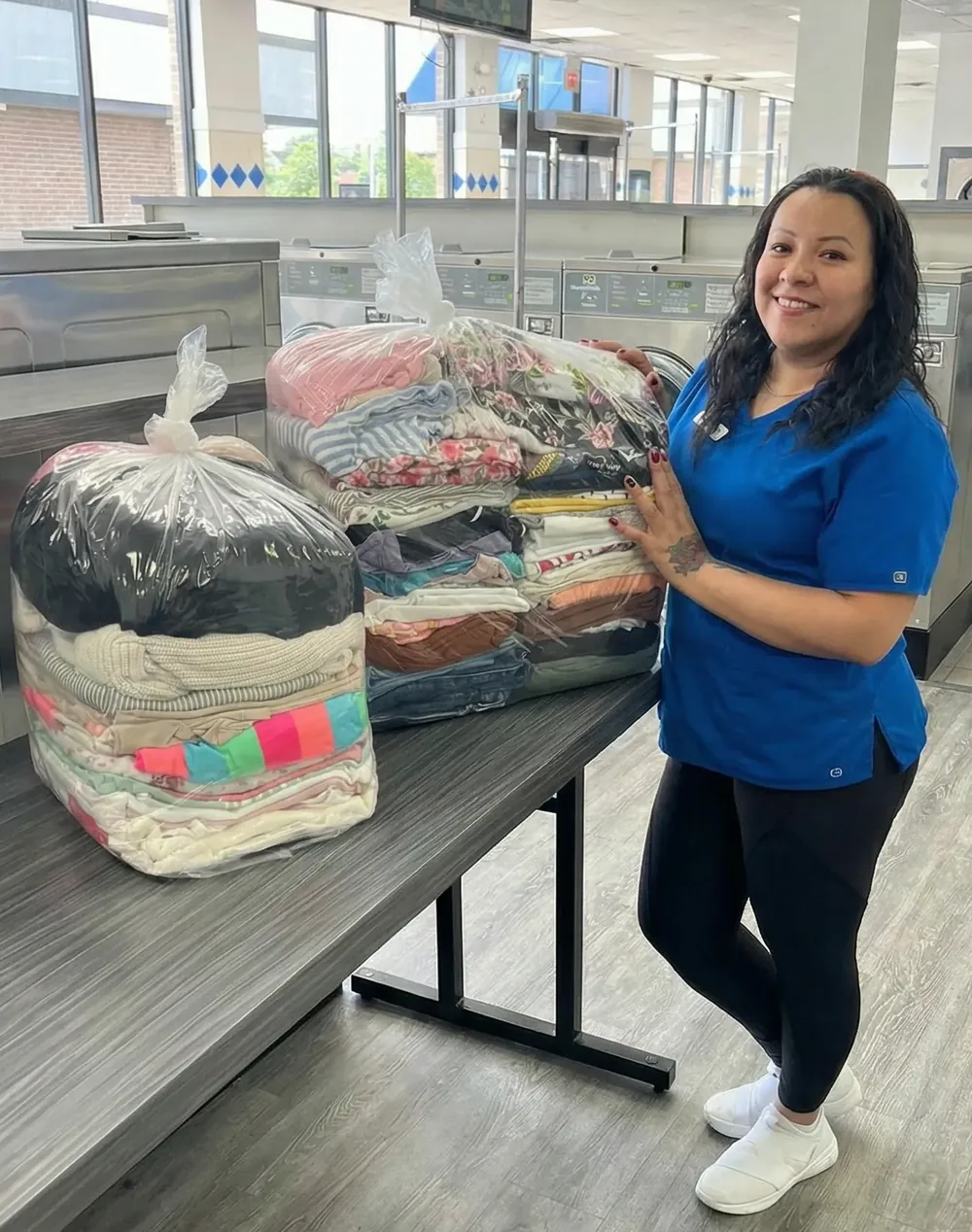 A Drop & Dash team member with two orders of clean, folded laundry ready for delivery